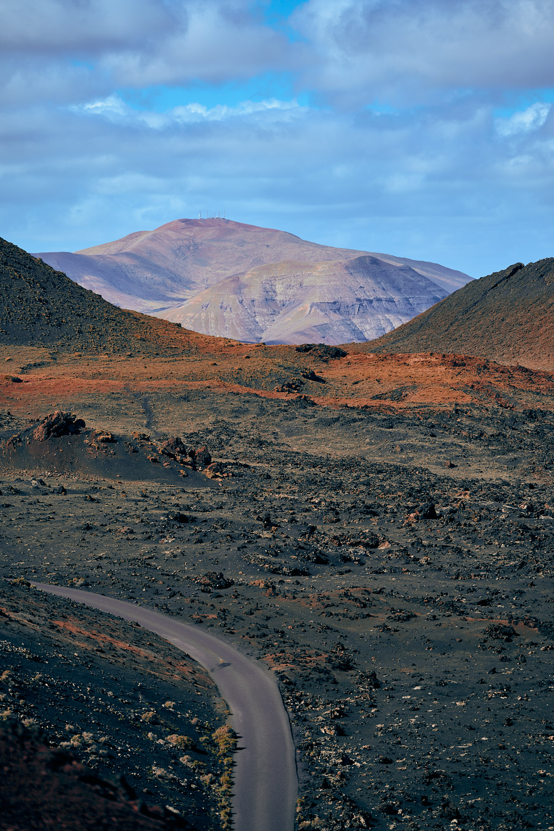 Paisaje volcánico con carretera serpenteante y montaña al fondo